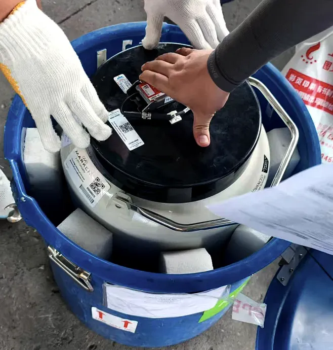 Two people in work gloves opening a sealed drum to draw a sample, with the accompanying paperwork alongside