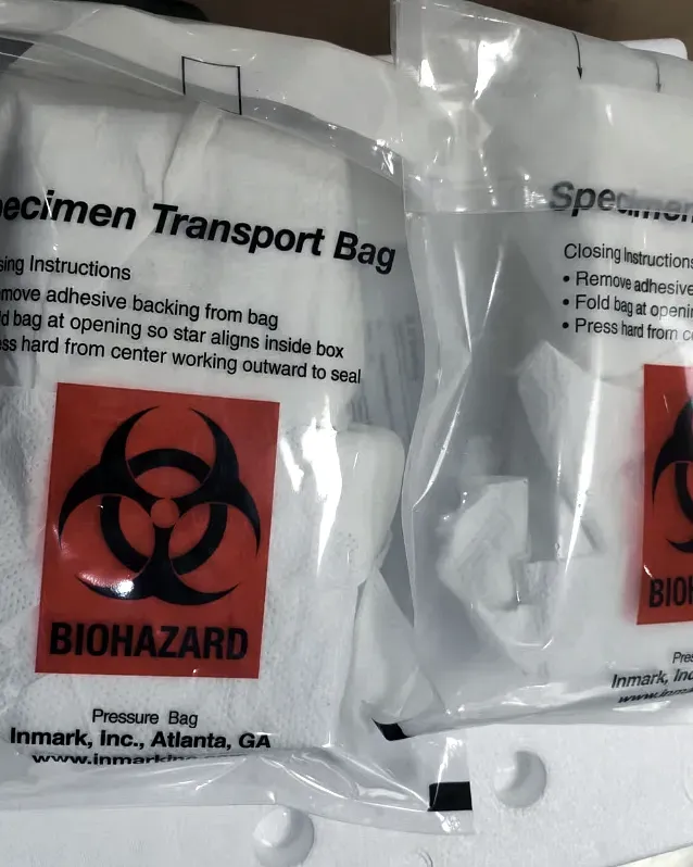Two specimen transport bags carrying biohazard marks, laid flat on packing material