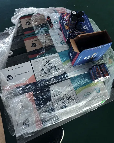 A stretch-wrapped pallet of beer cartons with one carton open at the top